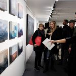 A photograph of visitors to a solo exhibition by Donna Giraud viewing various pieces of her art.