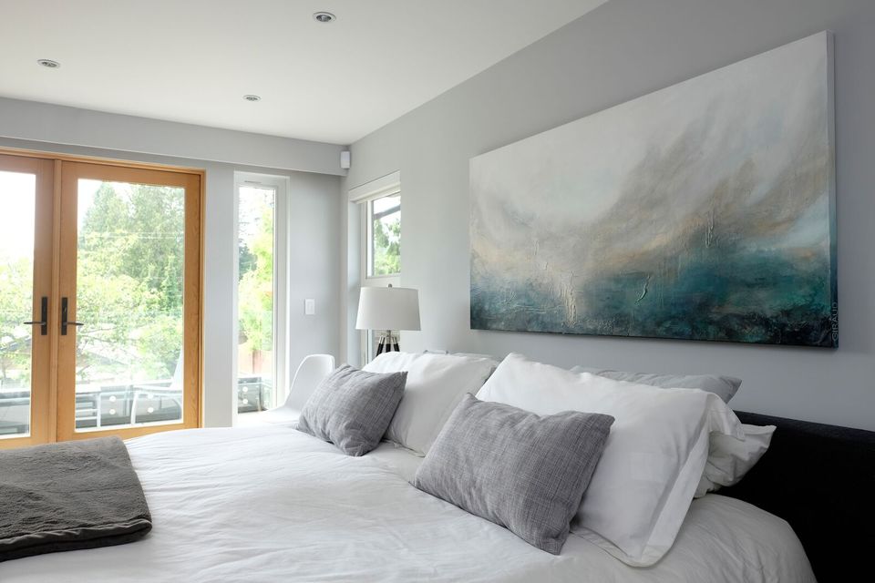 A photo of a bedroom with one of Donna Giraud's acrylic paintings called "LIFTH" hanging on the wall.