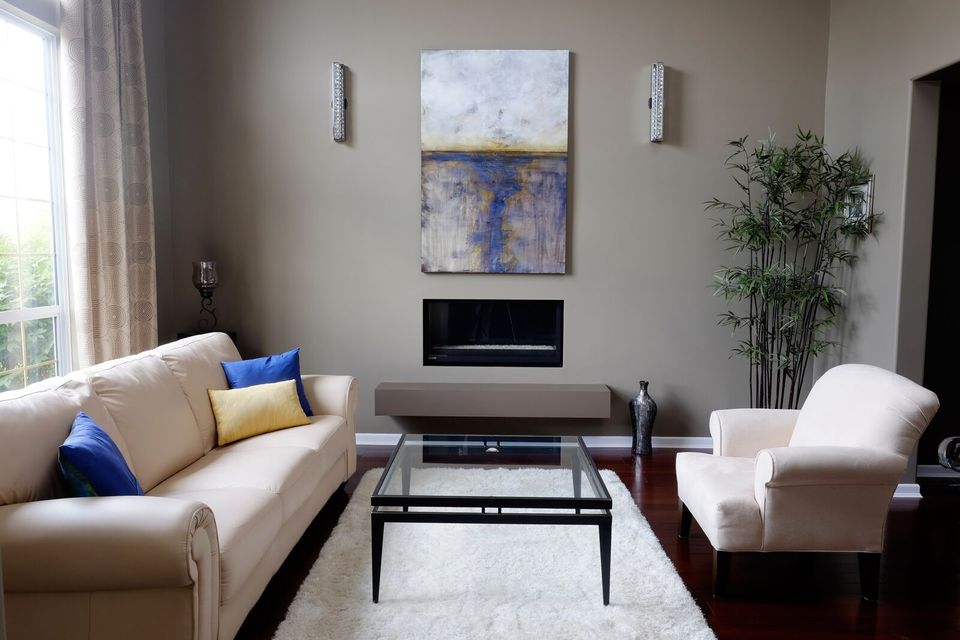 A interior photo of a livingroom with one of Donna Giraud's paintings hanging on the wall, called "REHTZ".