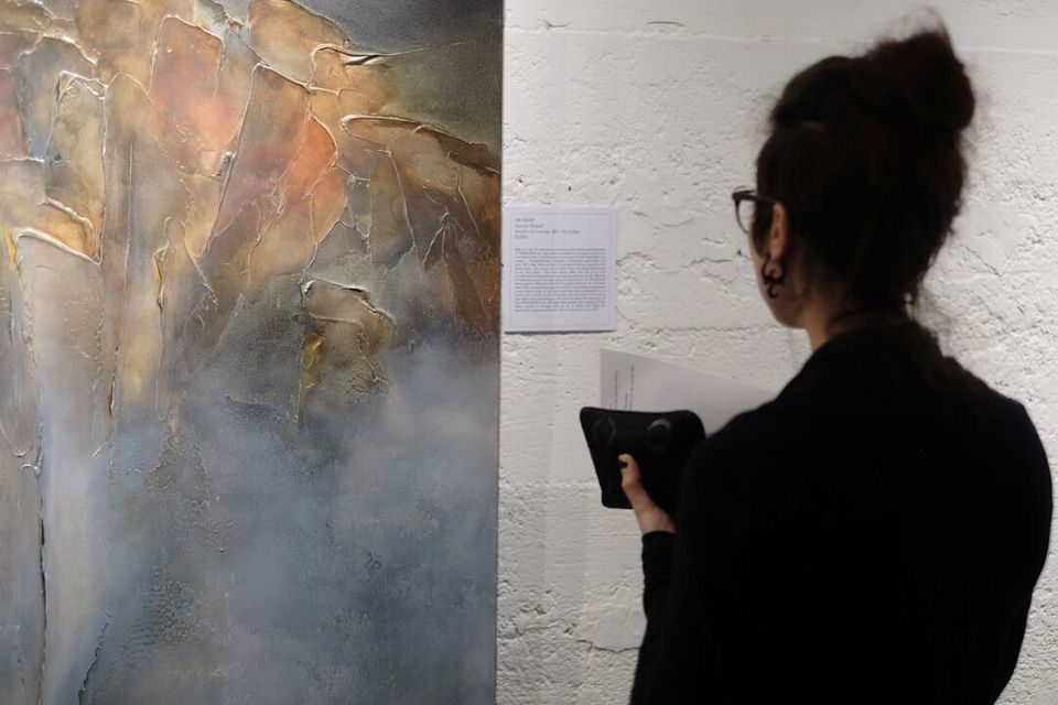 A photo of one of Donna Giraud's paintings being viewed by a guest at the exhibition.